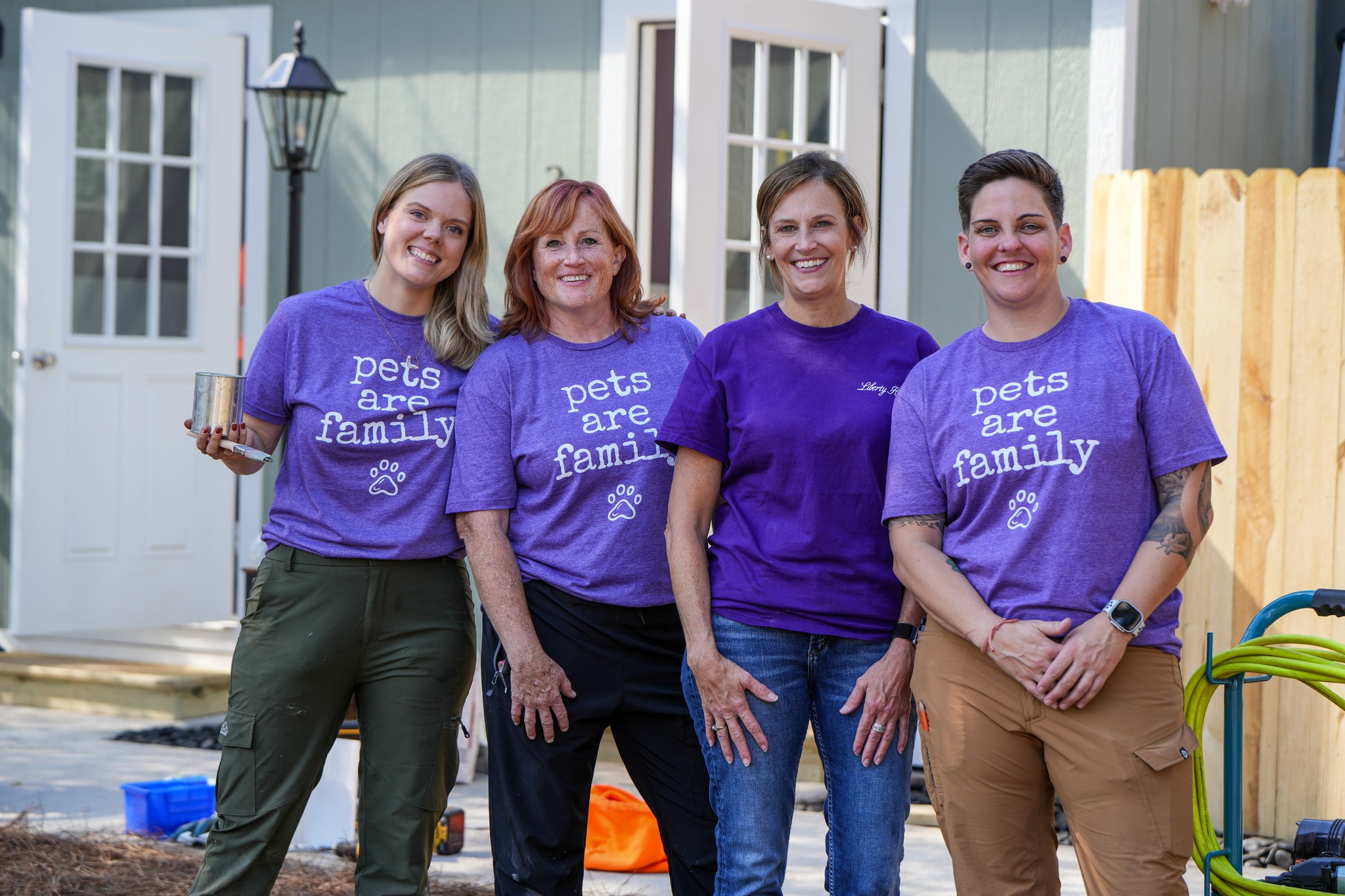four women wearing purple shirts in front of a shelter